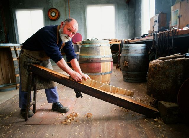A cooper shaping a stave by hand in his workshop