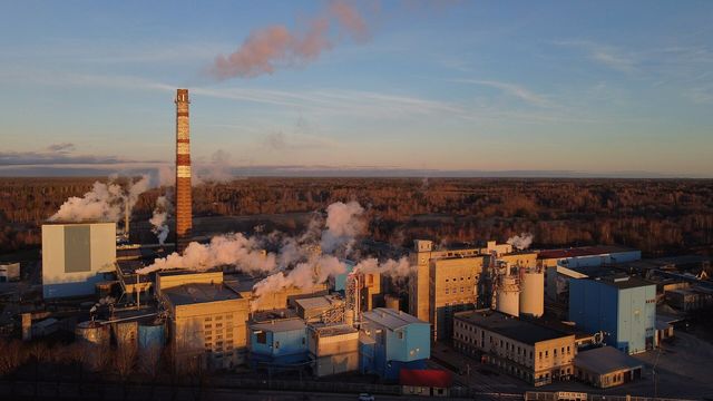A pulp and paper mill at dusk, with steam rising from the plant
